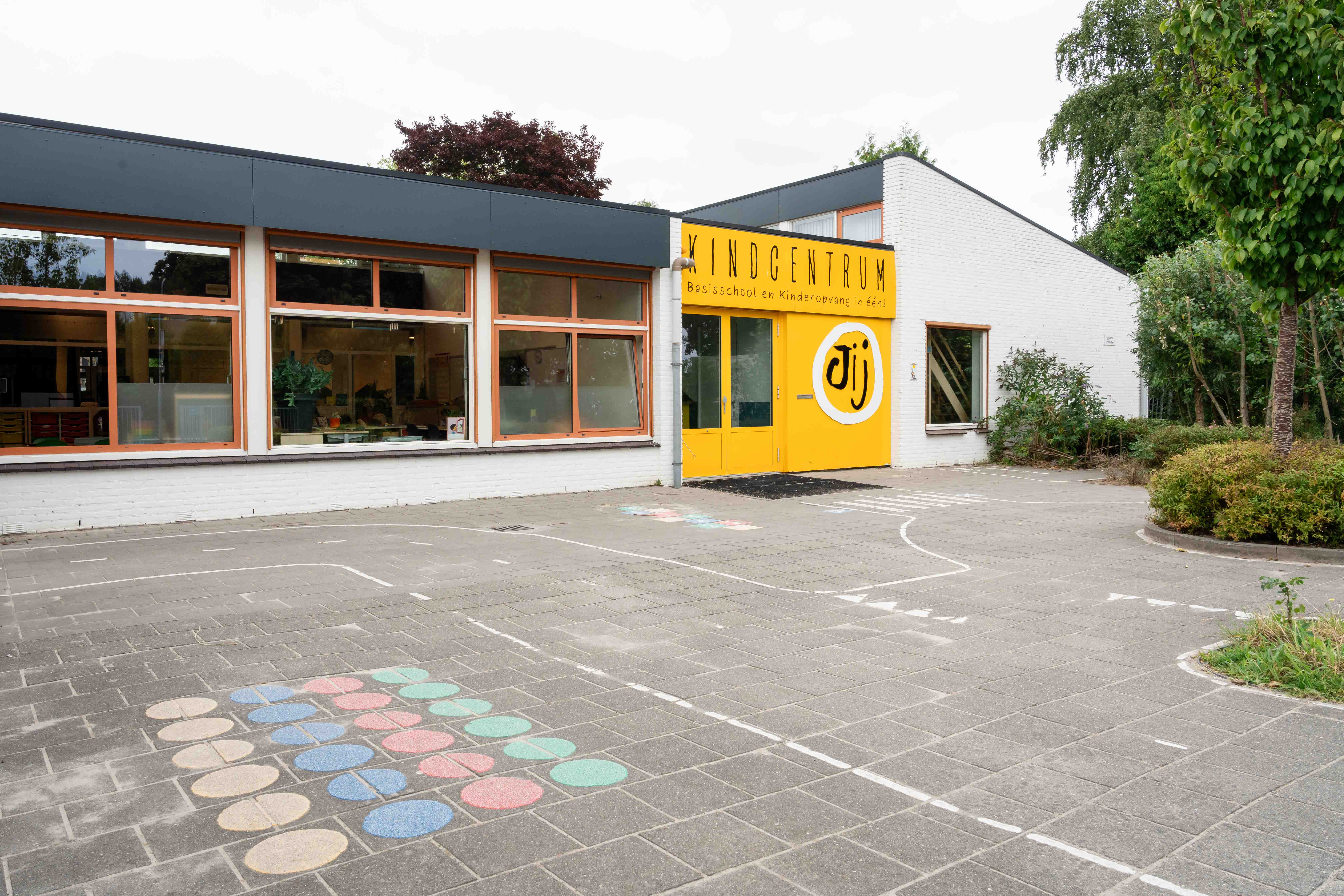 Het schoolgebouw van Kindcentrum Jij met het aangrenzende schoolplein in Terheijden.